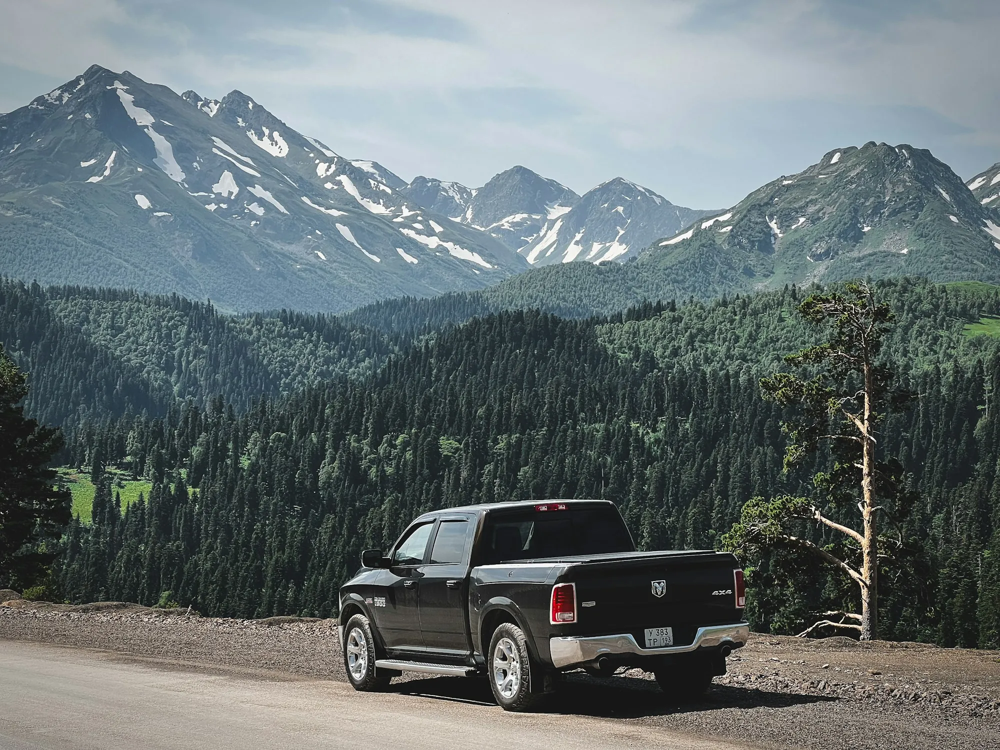 Pickup truck parked on a mountain road under clouds