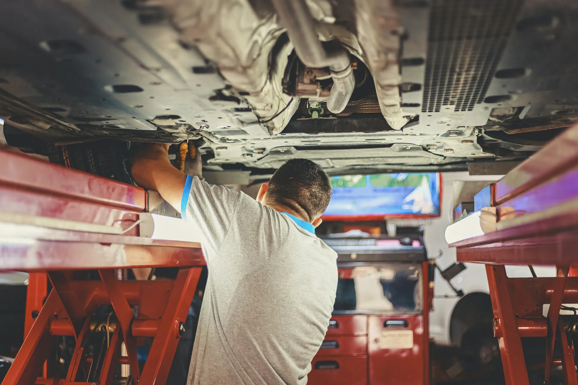 Technician inspecting the underside of a car on a lift