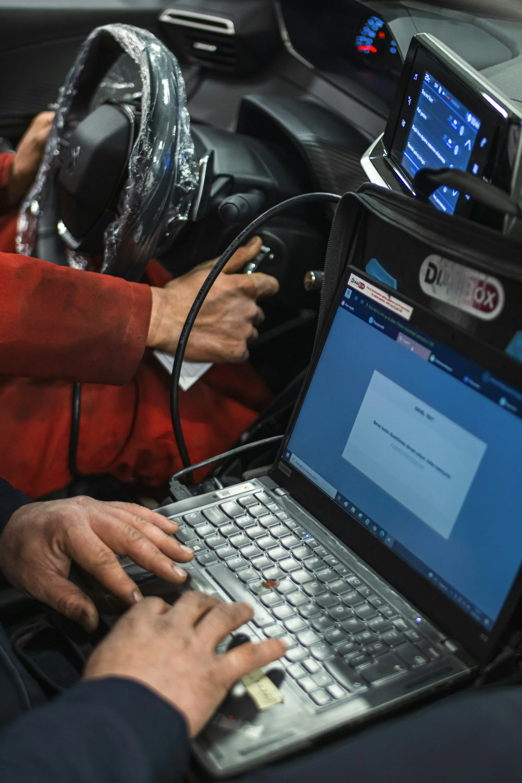 Technician running diagnostic software on a laptop inside a vehicle